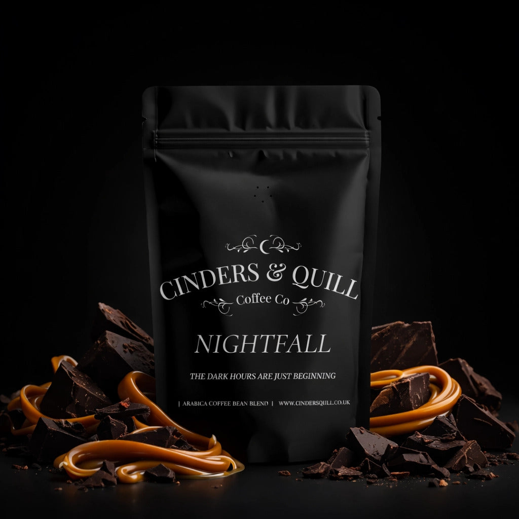 Black coffee bag labeled 'Cinders & Quill Coffee Co Nightfall' with chocolate pieces and caramel on a dark background.